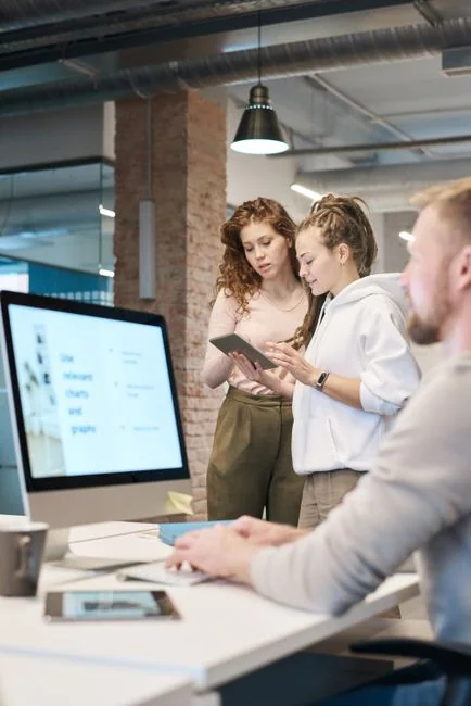 Une équipe variée travaillant ensemble sur des stratégies de marketing digital à une table, avec des ordinateurs portables et des tablettes.